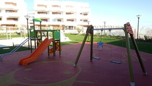 Un'area giochi con uno scivolo, altalene e una struttura per arrampicarsi.