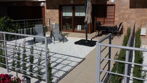 Una moderna terrazza esterna con area salotto, tavolo e pergola.