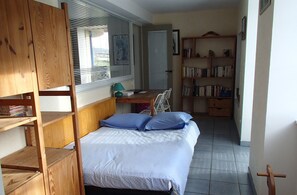 Cozy bedroom with a single bed, wooden wardrobe, and desk area.