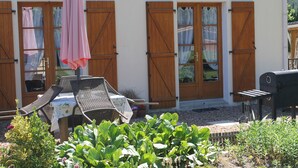 A patio with a table and chairs, a grill, and a garden with plants. - Les Pins at La Cerniére with shared pool (Deneze sous Le Lude)