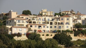 Un immeuble résidentiel à plusieurs étages doté de balcons, d’une terrasse sur le toit et d’un jardin aménagé.