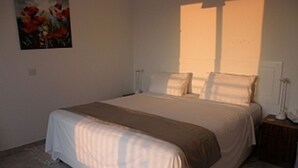 Une chambre à coucher avec un grand lit, une table de chevet, une lampe et un tableau au mur.