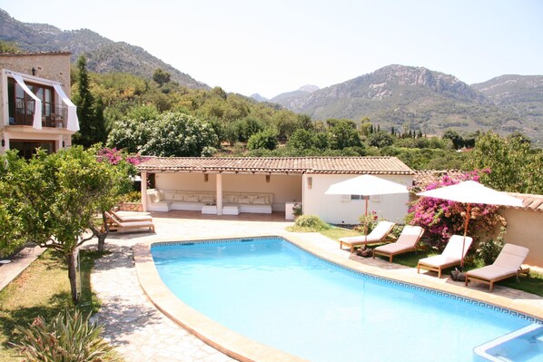 A pool area with lounge chairs and umbrellas, surrounded by greenery and mountains in the background. - Beautiful Country Villa With Private Pool & Huge Garden (Sóller)