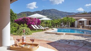 A poolside area with lounge chairs, a pool, and a mountain backdrop. - Beautiful Country Villa With Private Pool & Huge Garden (Sóller)