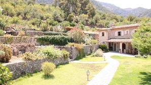 A stone-walled garden with a pathway leading to a building with a tiled roof and arched windows. - Beautiful Country Villa With Private Pool & Huge Garden (Sóller)