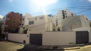 Un edificio moderno con fachada blanca, dos puertas de garaje de color oscuro y un cielo despejado.