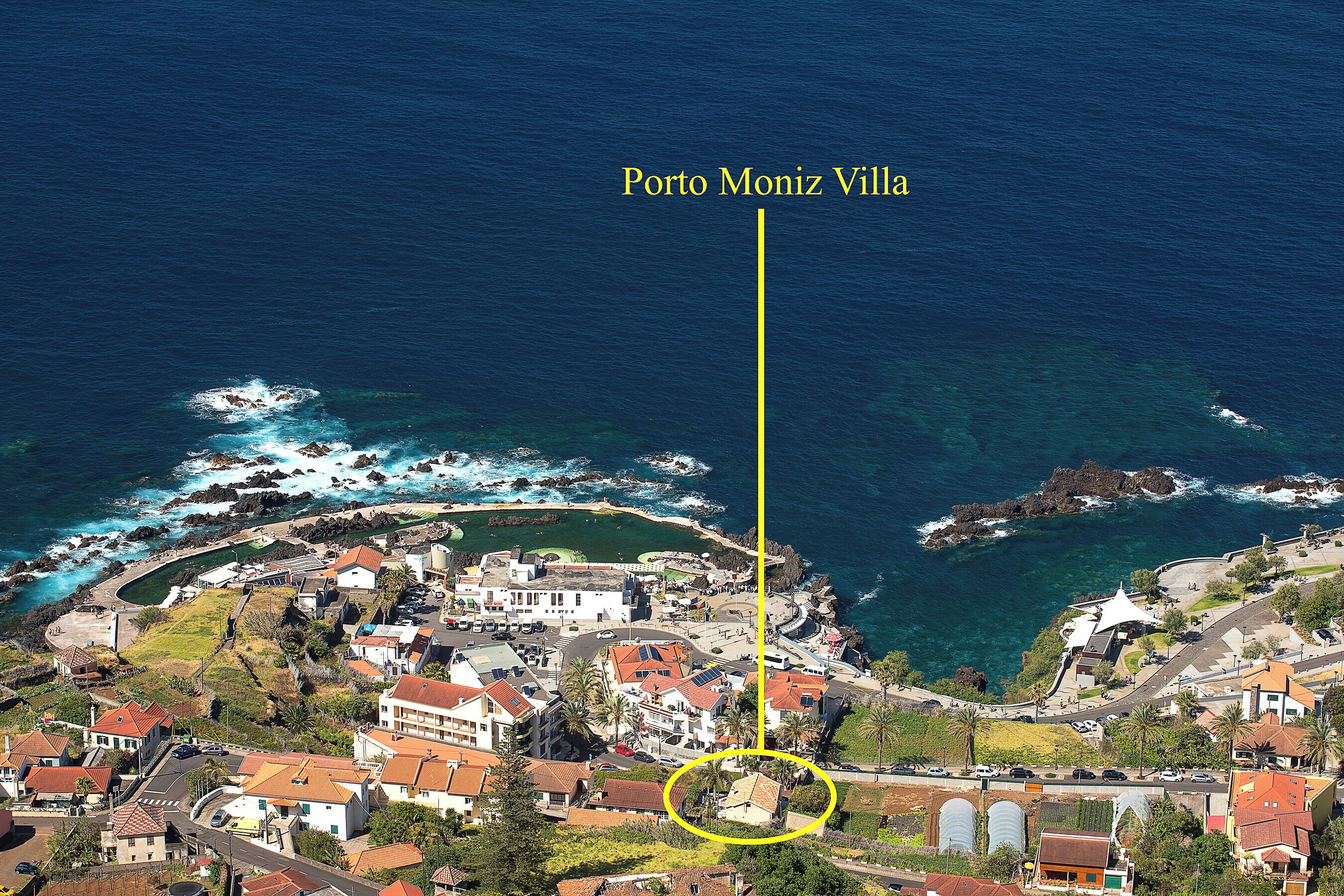 An aerial view of Porto Moniz, highlighting the coastal town layout, buildings, and the surrounding ocean.