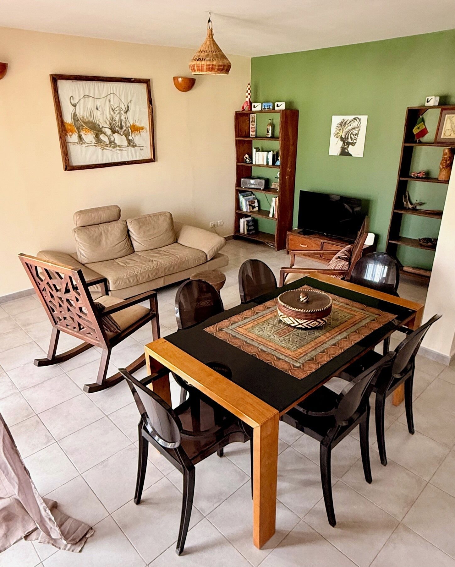 A living room with a sofa, dining table, chairs, a television, and a bookshelf.