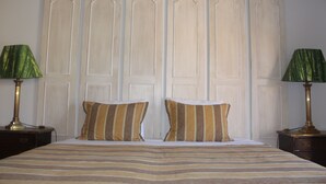 A bed with striped bedding, two pillows, and a headboard with vertical panels. - Villas Marim Heron House  (Olhão)