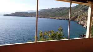 Une vue sur la côte, prise depuis une fenêtre donnant sur la mer et les montagnes.