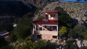 Une maison de montagne à deux étages, avec un toit rouge, un balcon et des panneaux solaires.