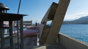 Une terrasse en bois offrant une vue sur la mer et les montagnes.
