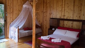 Une chambre dans une cabane en bois, avec un lit à baldaquin, un lit séparé et une table de chevet avec une lampe.