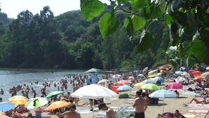 Een druk strand met veel parasols en mensen die van het water genieten.