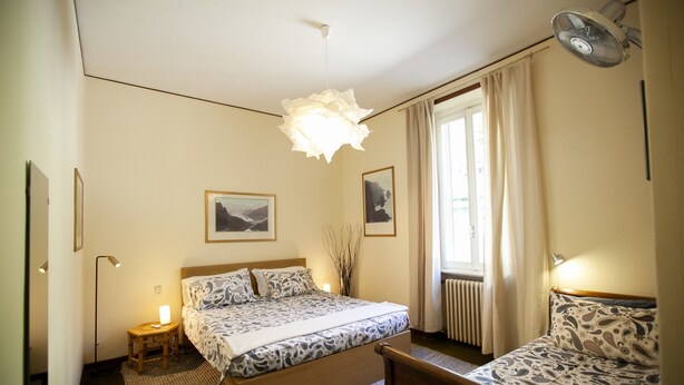 Een hotelkamer met een bed, een bank, een staande lamp en een plafondventilator.