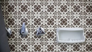 Een badkamer met patroon betegelde vloeren, een wastafel en twee kraanwerk.