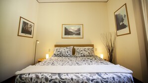 Een slaapkamer met een bed, twee nachtkastjes, een wandlamp en kunst aan de muur.