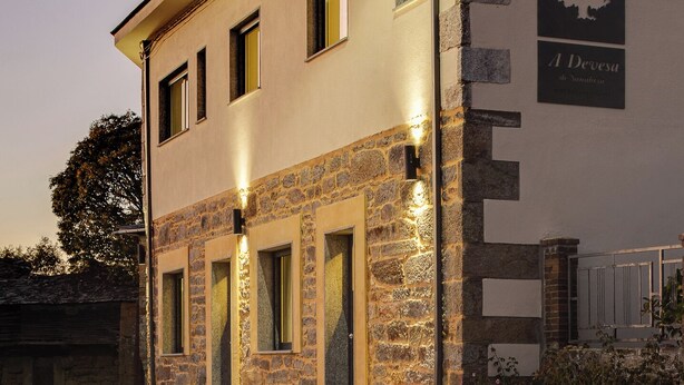Un edificio con fachada de piedra, varias ventanas y un letrero que dice "A Devesa".