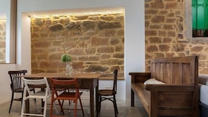 Comedor con pared de piedra, mesa y sillas de madera.