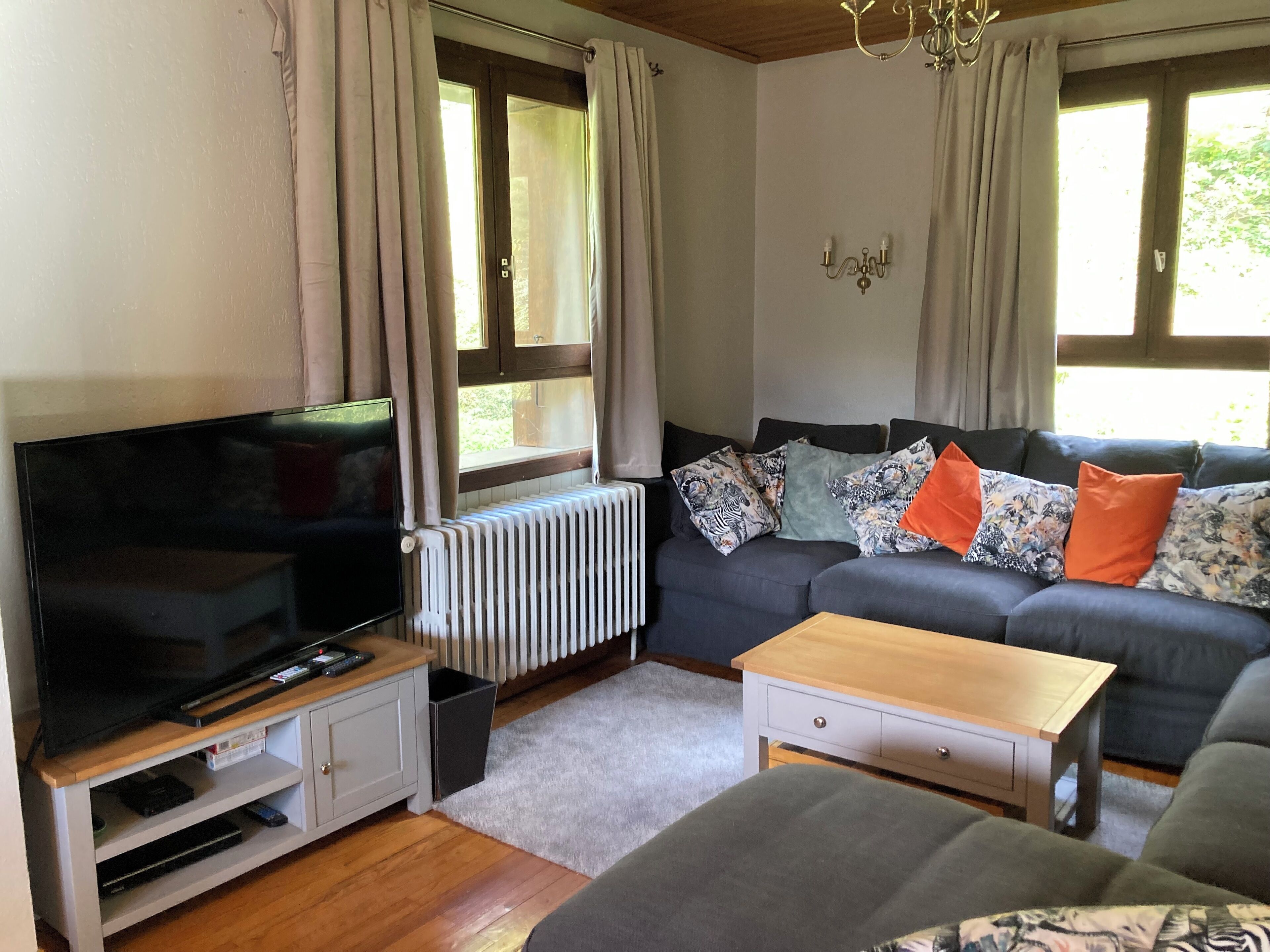 A living room with a TV, sofa, and a radiator.