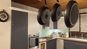 Une cuisine moderne avec des meubles de couleur grise, un plafond en bois et des casseroles suspendues.