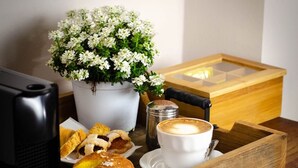 Une boîte en bois avec un intérieur blanc, une tasse à café, des pâtisseries, un pot de fleurs et un salier.