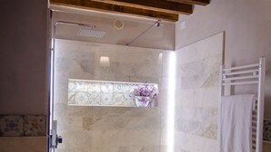Une douche avec une porte en verre, un plafond en bois et un mur carrelé.