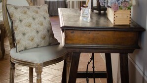 Une pièce au style rétro, avec une table en bois, une chaise dotée d’un coussin à motifs, une lanterne décorée de fleurs et une fenêtre ornée de rideaux.