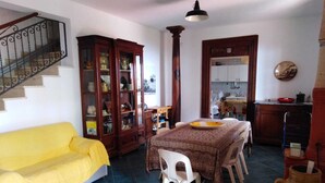 Un coin repas avec une table dressée pour quatre personnes, un canapé jaune et un escalier muni d’une rampe.