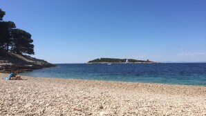Una playa de guijarros con cielo azul despejado y mar tranquilo.