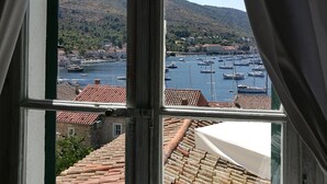 Una ventana con vistas a un puerto, edificios y un paisaje montañoso.