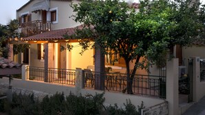 Una casa de dos pisos con balcón, comedor y jardín.