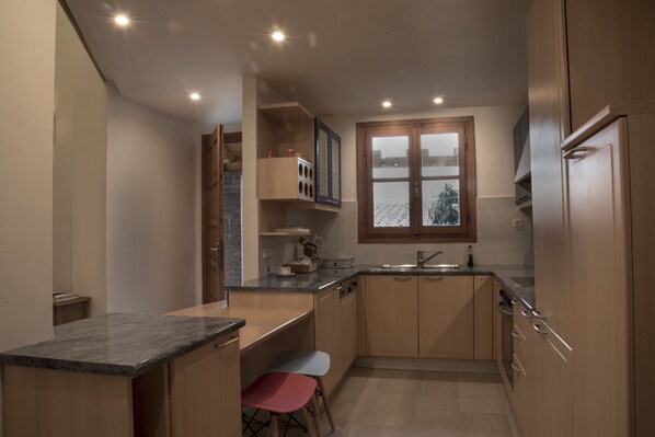 Cocina compacta con armarios de madera, encimera de granito y ventana con vista a la ciudad.