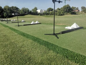 A golf course with neatly trimmed grass, multiple tees, and a clear sky.
