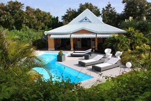 Una casa moderna con piscina, rodeada de exuberante vegetación.