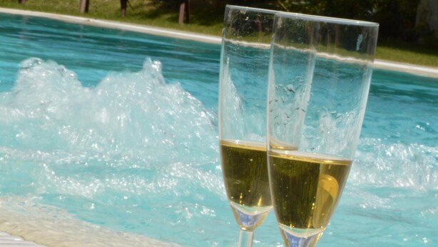 A poolside setting with two champagne flutes and a rose on a white table. - Villa with private pool in Lucca, special offers! (Capannori)