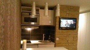 Een moderne keuken met een inbouwoven, magnetron en een televisie aan de wand.