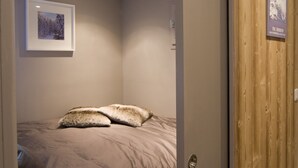 Een slaapkamer met een bed, een houten deur en een lijst met een foto aan de muur.