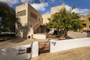 A building with a beige facade, a staircase leading to a covered area, and a tree in the foreground. - CAN NOVES-Fabulous villa in a central and quiet area (Sant Francesc de Formentera)