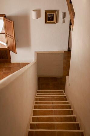 A staircase with white walls and brown tiles, leading to a lower level.