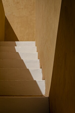 Un escalier aux marches blanches menant vers le haut, entouré de murs de couleur beige.
