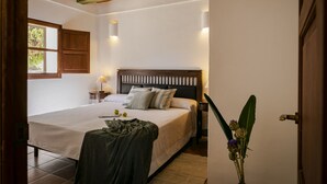 Une chambre à coucher avec un lit, des tables de chevet, une fenêtre et une porte.