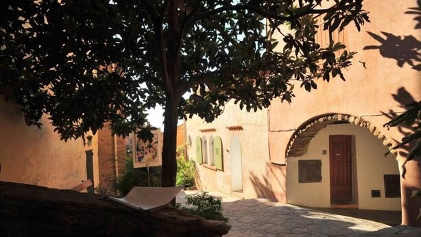 Una estrecha calle adoquinada bordeada por edificios con puertas arqueadas y contraventanas.