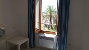 Habitación de esquina con ventana, radiador y una pequeña mesa blanca.