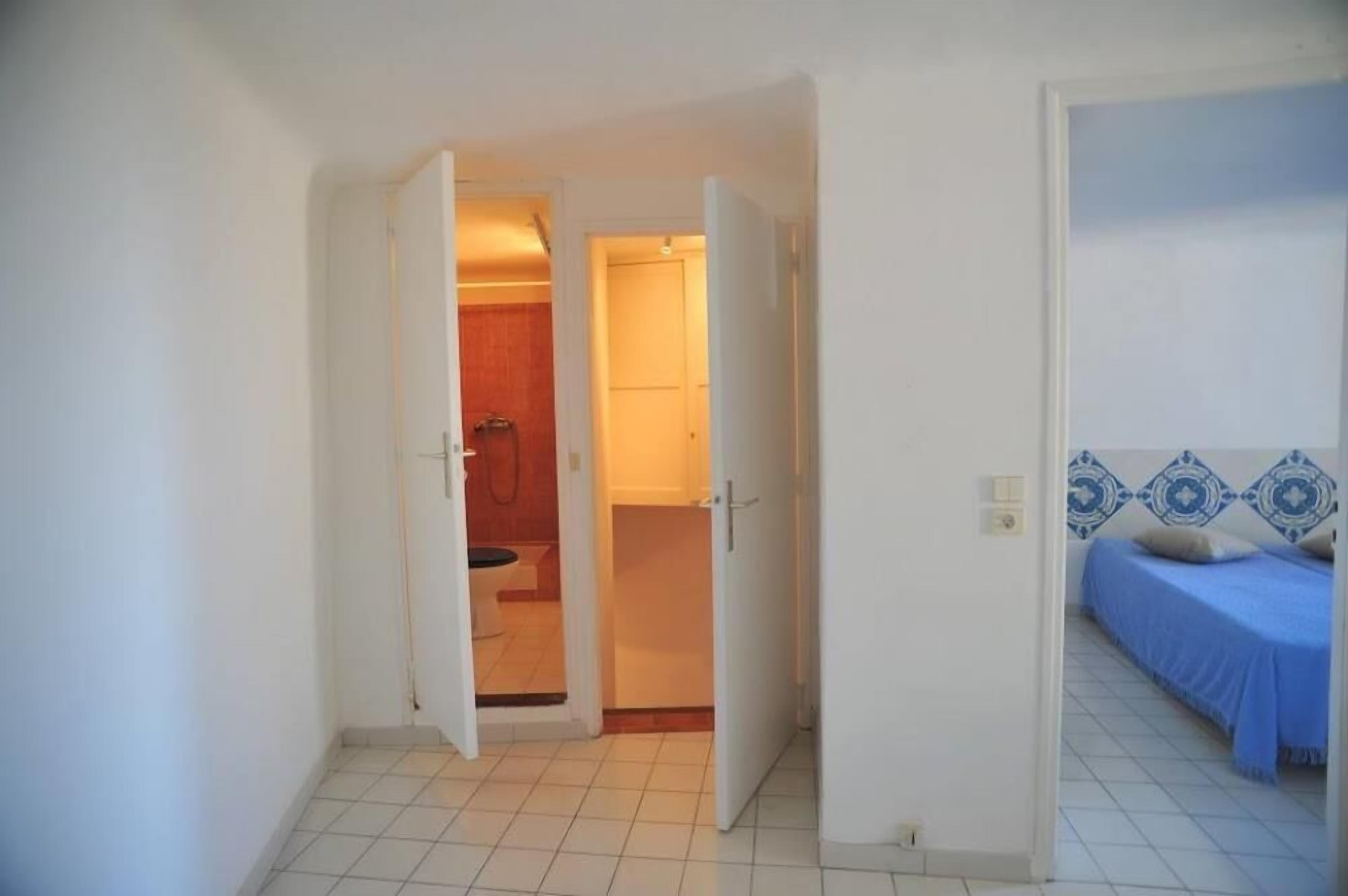 A room with a bed, a bathroom, and a door leading to another room.