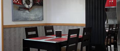 Ein moderner Essbereich mit einem rechteckigen Tisch, schwarzen Stühlen und einer Pendelleuchte.