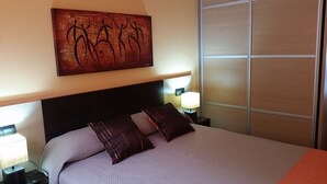 A hotel room with a large bed, two bedside tables, a wall-mounted artwork, and a sliding door.