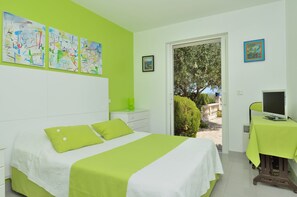 Un dormitorio con una cama, un escritorio con ordenador y una puerta que da a un espacio exterior.