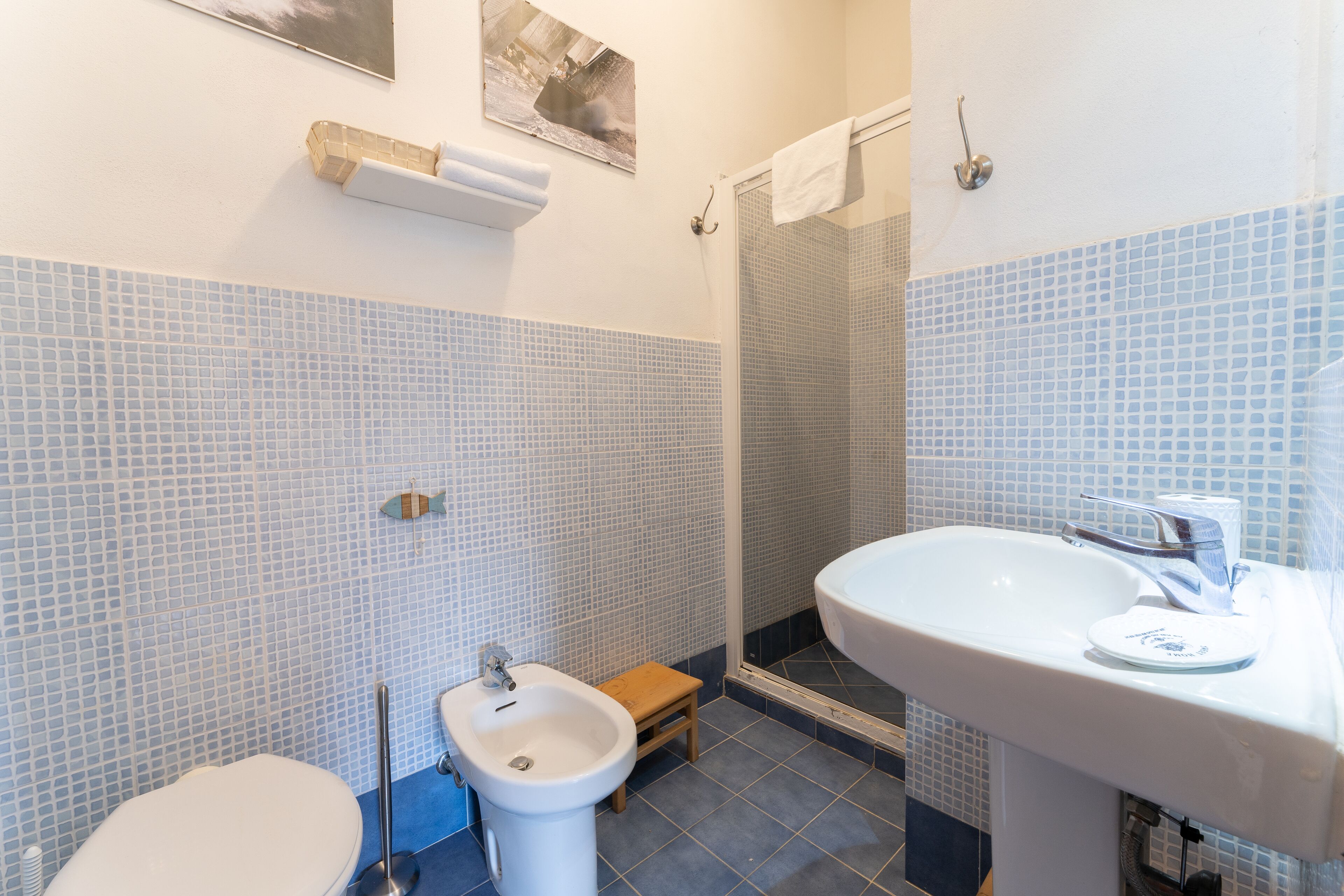 A bathroom with a toilet, bidet, sink, and shower.