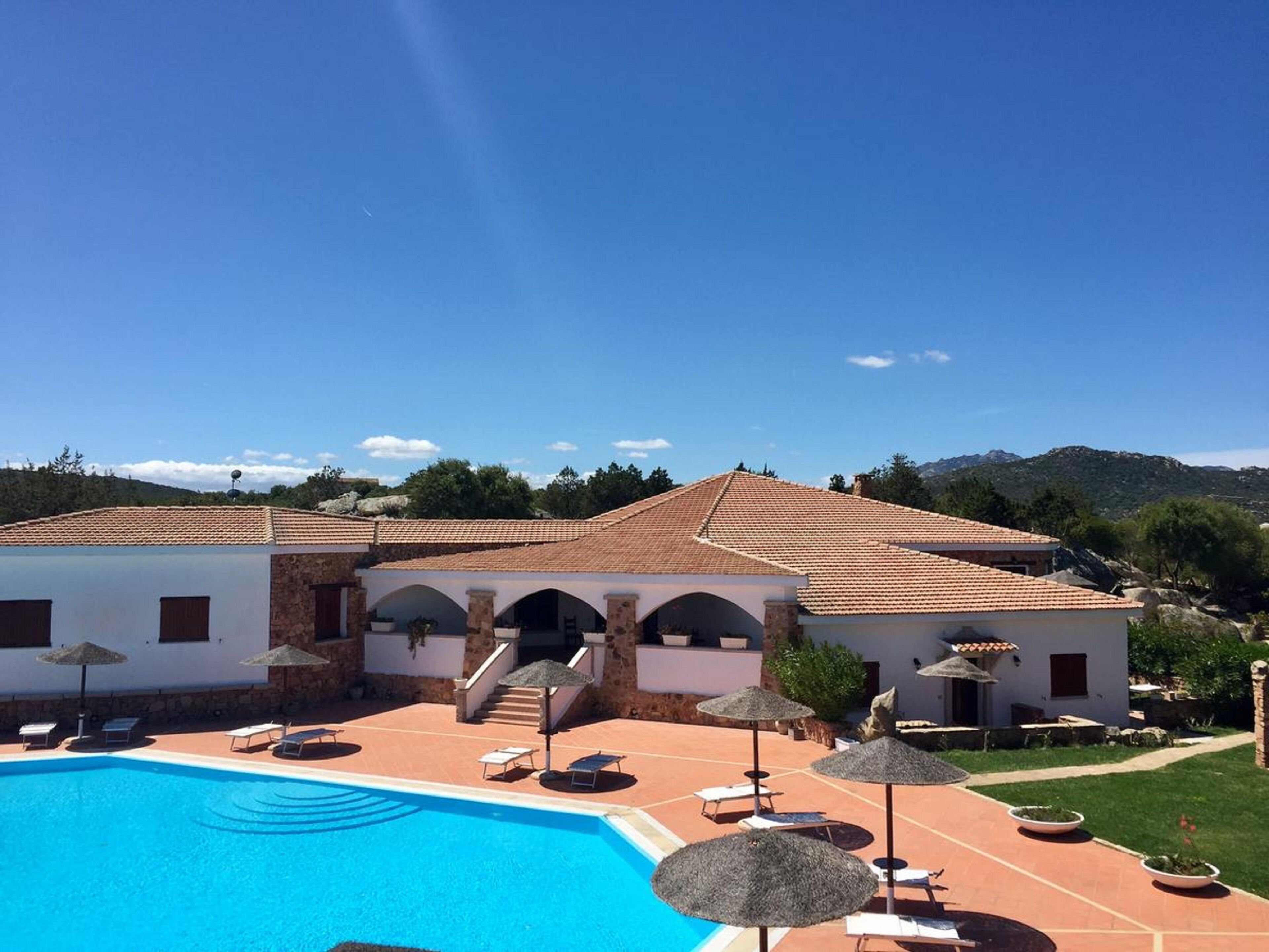 A resort with a swimming pool, sun loungers, and umbrellas.